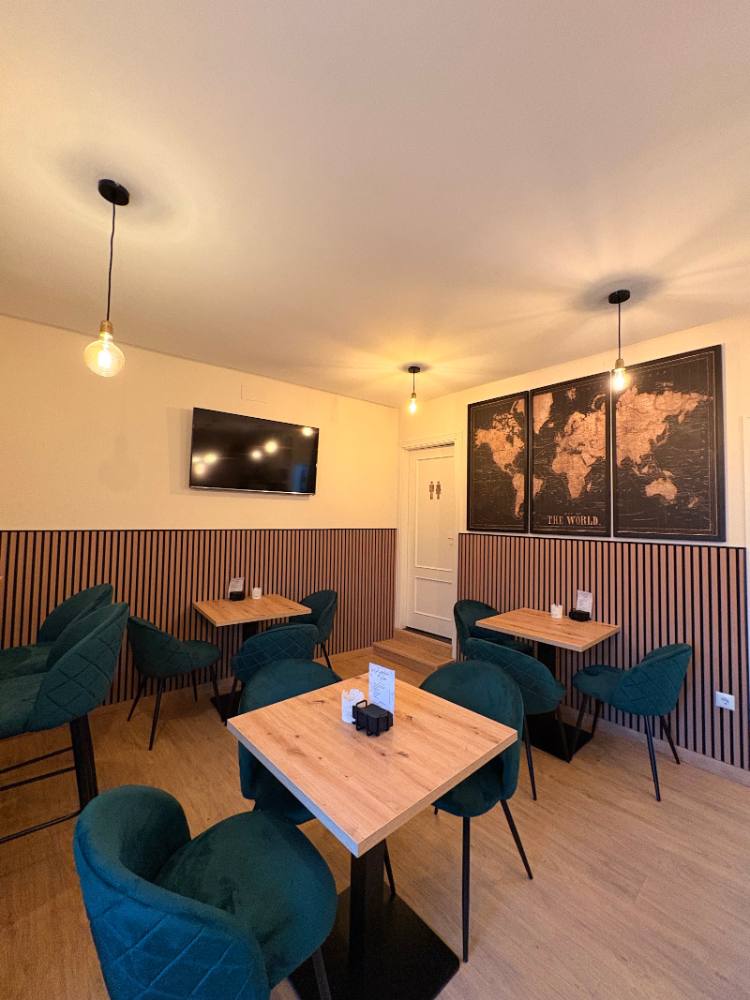 Comedor de La Parada de Hoyo con sillas verdes y mesas de madera